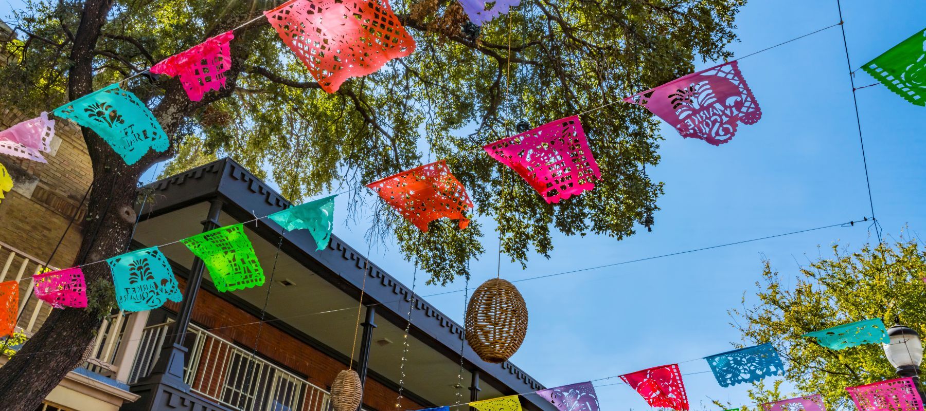 upward angle of a san antonio alleyway decorated with colorful paper decorations for fiesta