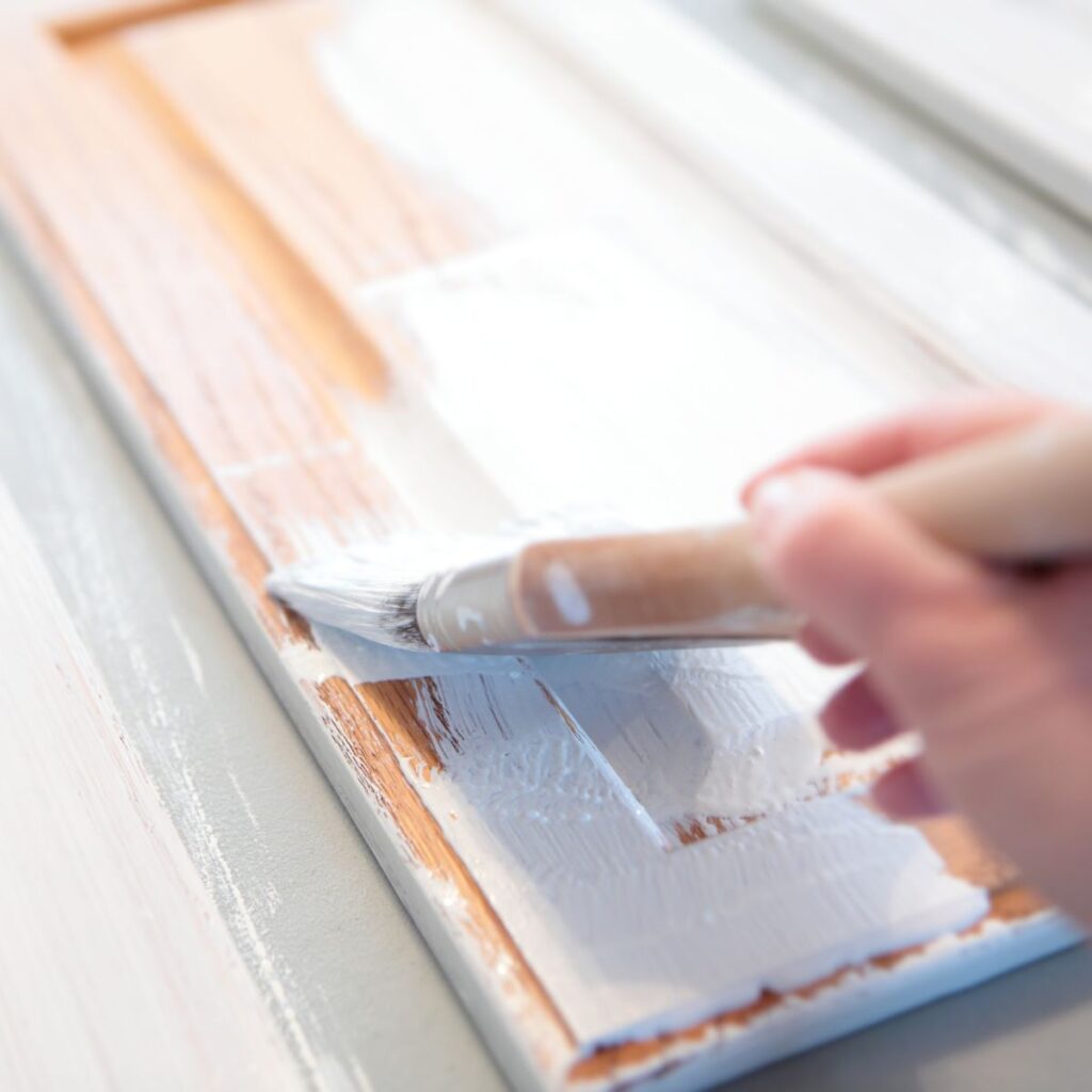 close up of paintbrush painting a cabinet white