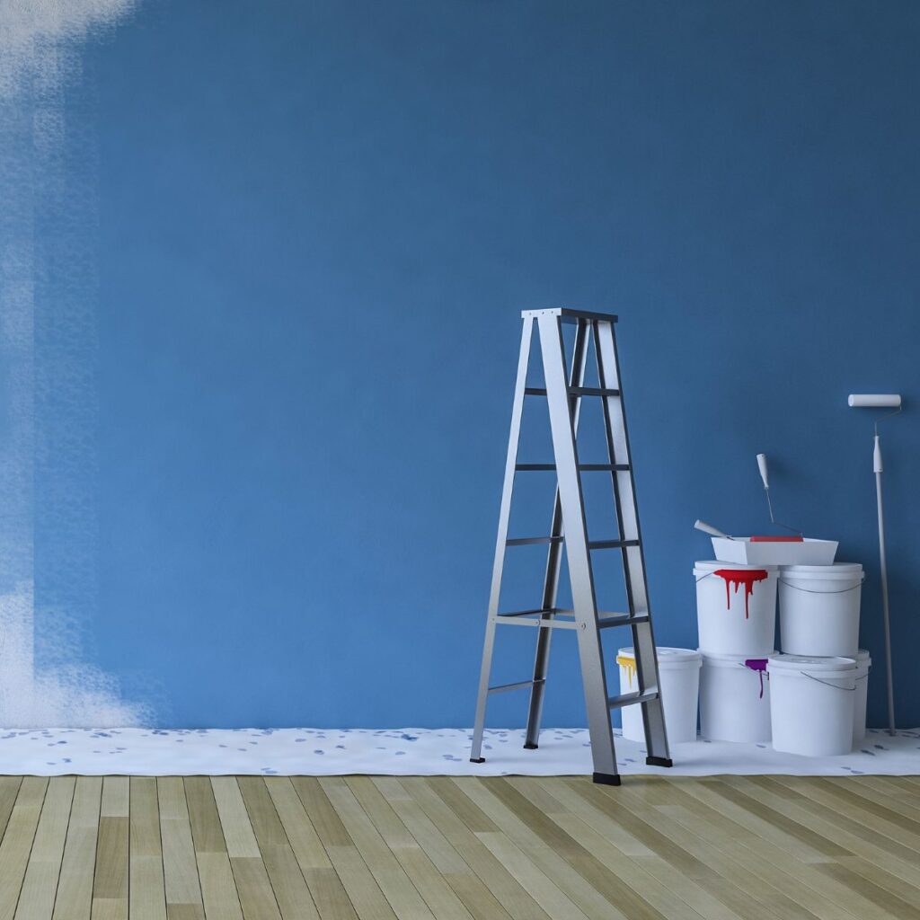 an interior wall partially painted blue. a ladder and paint buckets are on the floor