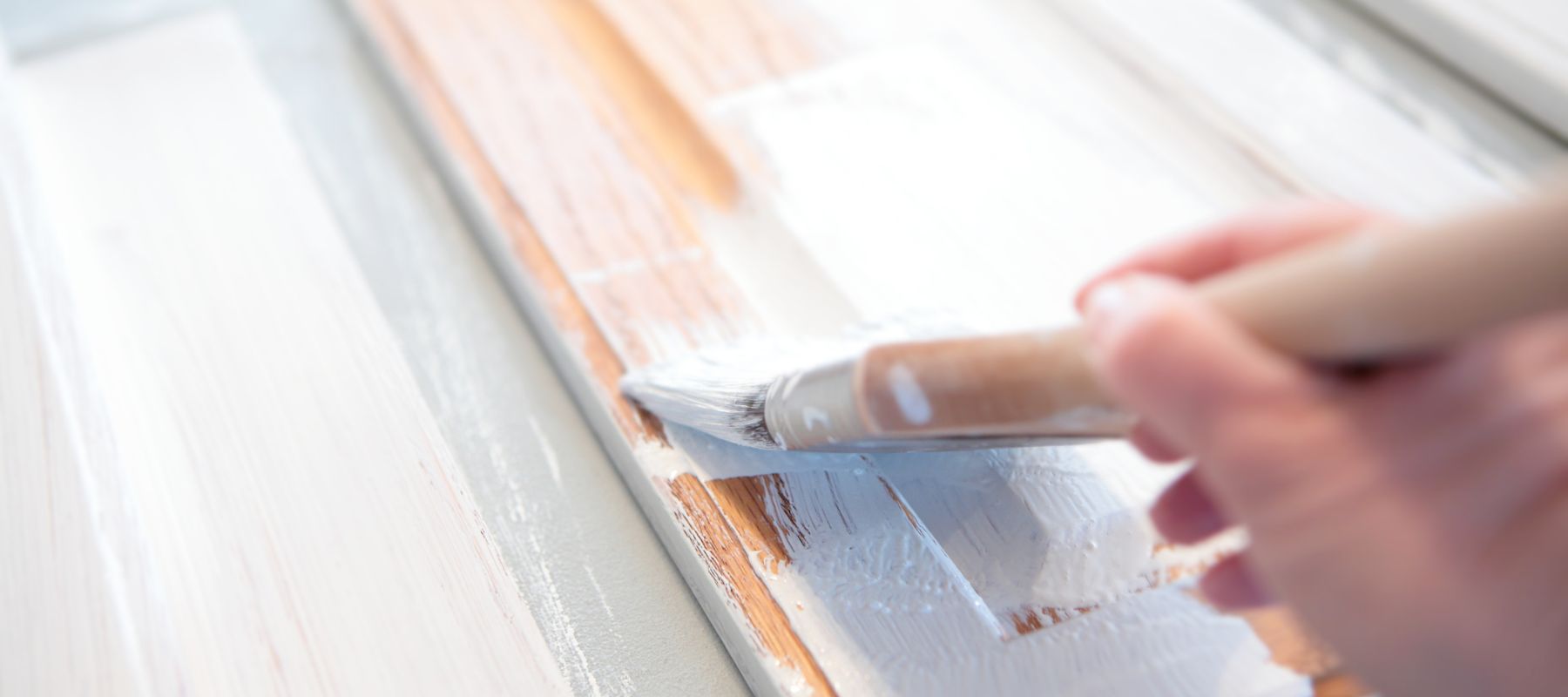 close up of paintbrush painting a cabinet door white
