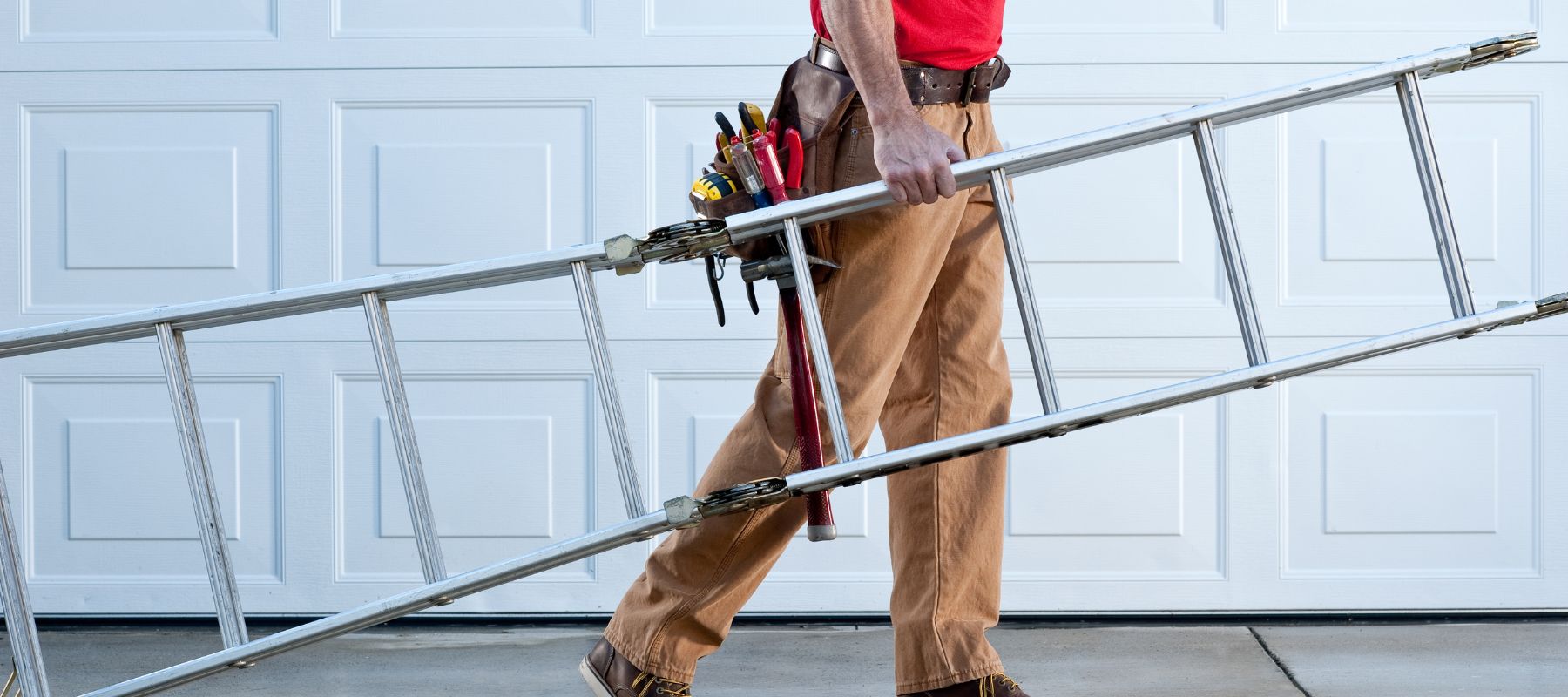 handyman with toolbelt carrying a ladder