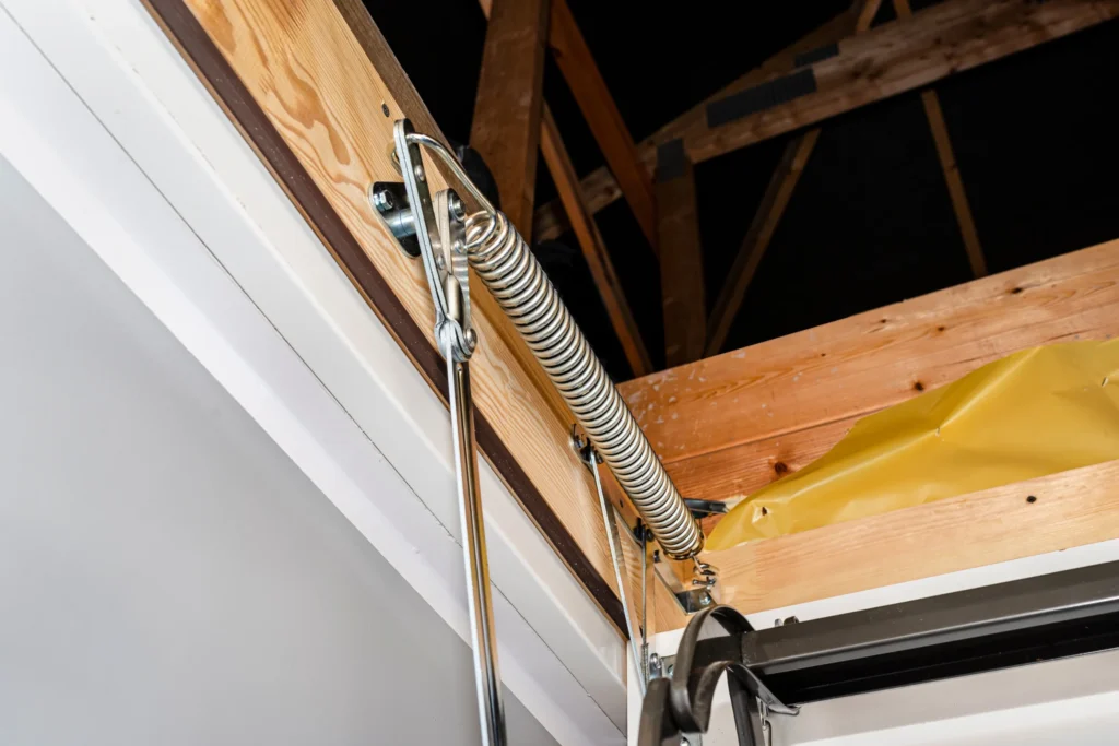 Close-up view of a metal spring mechanism on an attic ladder in San Antonio