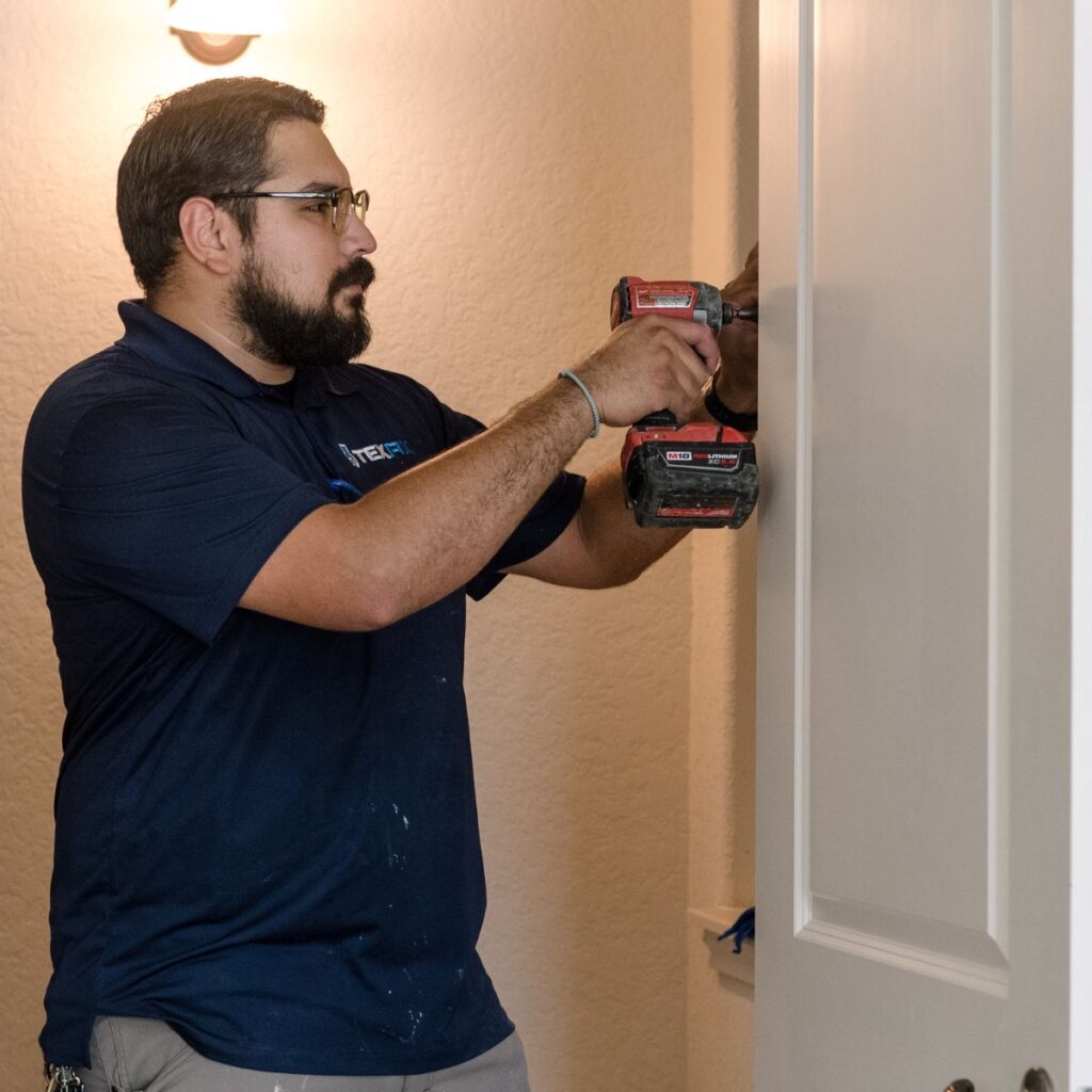 TexFix handyman using a drill to repair a door and secure a door frame