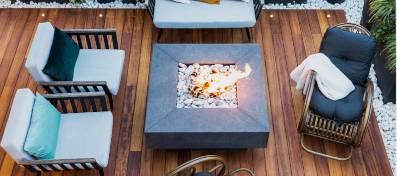 Modern outdoor deck with cozy seating and a central fire pit surrounded by decorative stones