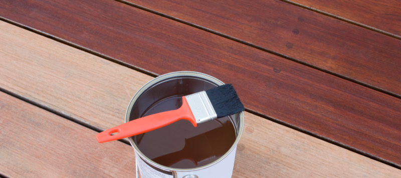 can of deck stain sitting on a deck near a recently painted deck
