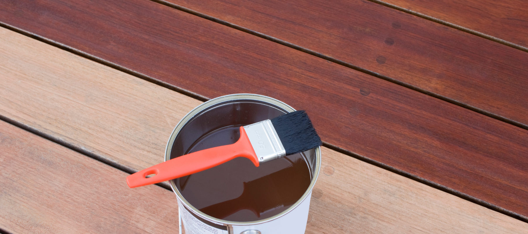 can of deck stain sitting on a deck near a recently painted deck